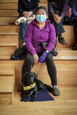 Masked attendee at Canadian Opera show sitting with their service dog looking directly at camera.