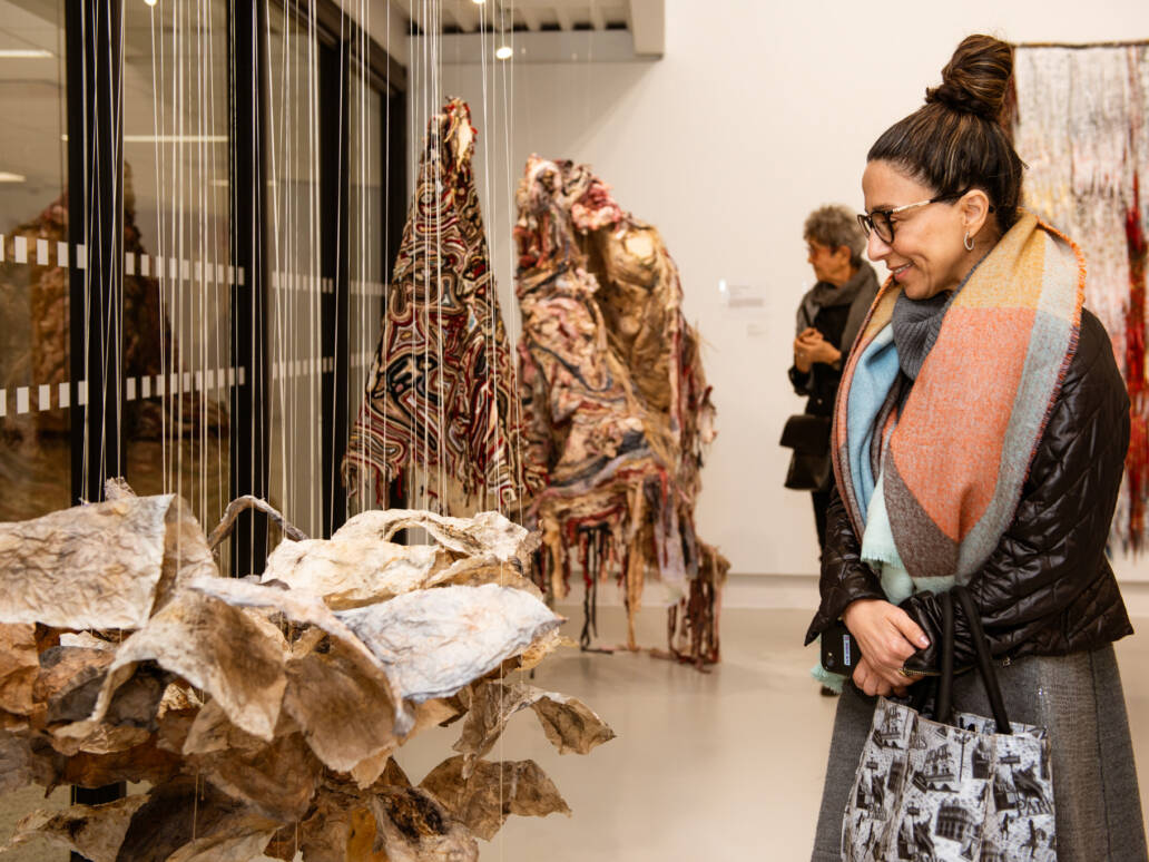 Woman examining textile art on display.
