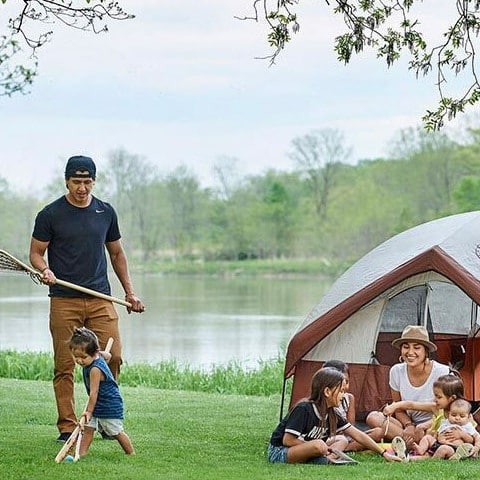 family at camping site with tent and river in the background