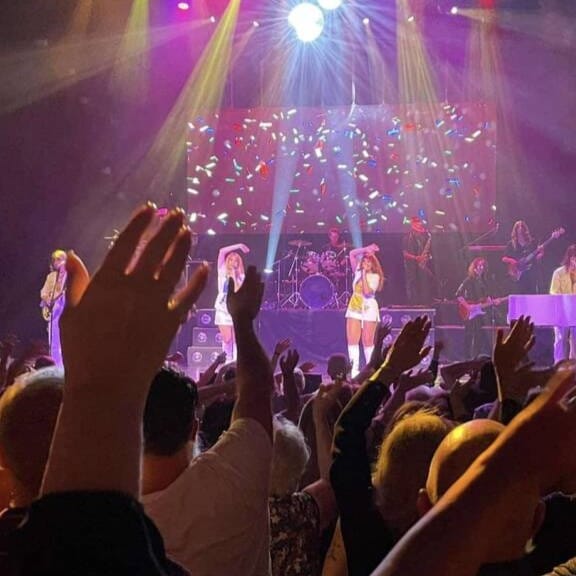 Concert with singers and crowd waving hands