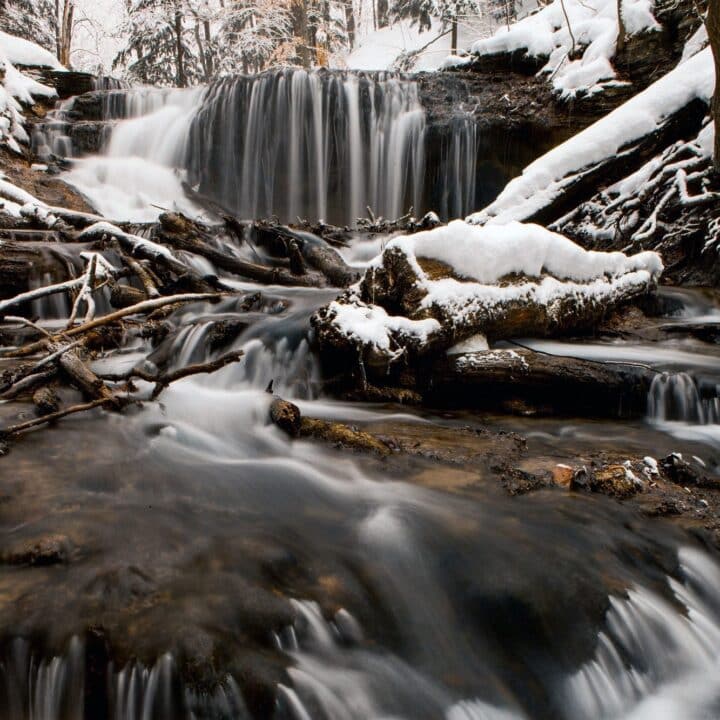 water flowing in a river with snow and trees all around